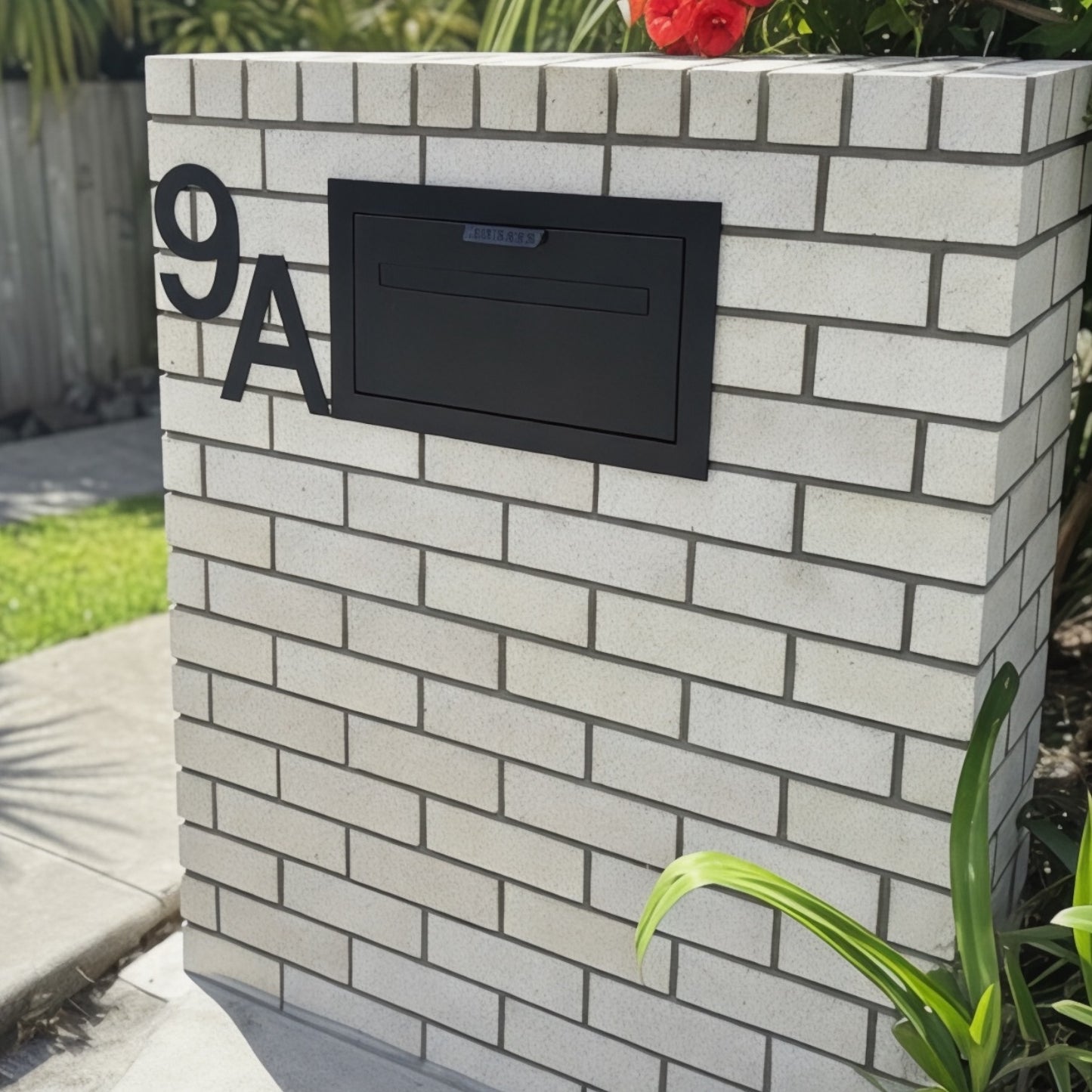 Black mailbox on a white brick wall with house number